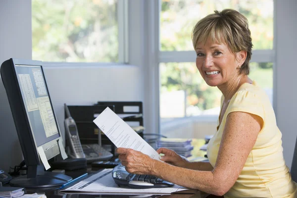 ホーム オフィス コンピューターと書類の笑顔の女性 — ストック写真