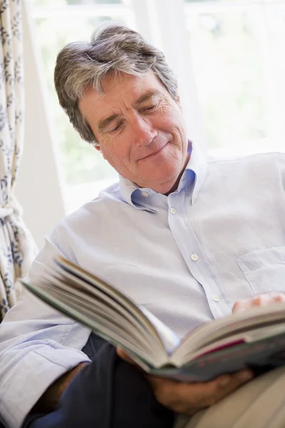在客厅里读的书微笑的男人 — 图库照片