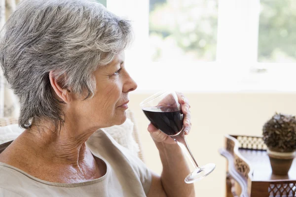 Женщина в гостиной с бокалом вина — стоковое фото