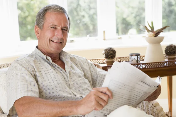 Adam gülümseyerek gazete okuma oturma odasında — Stok fotoğraf