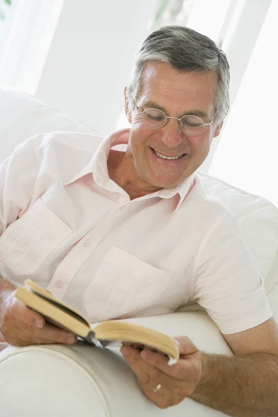 Man in woonkamer lezen boek glimlachen — Stockfoto