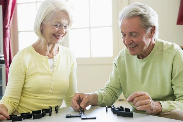 Couple playing dominos in living room smiling — Stock Photo, Image