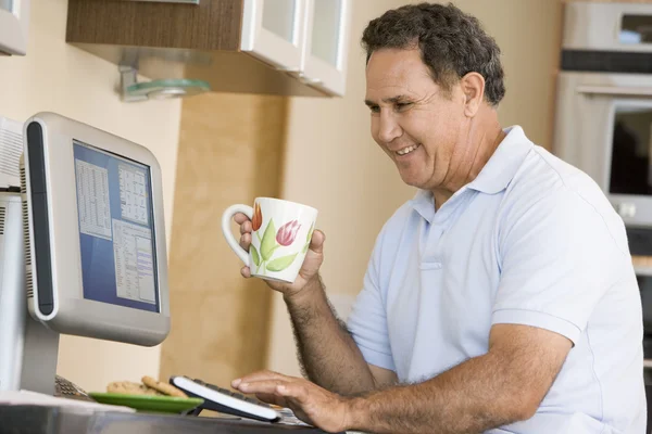 计算机和咖啡微笑的厨房的男人 — 图库照片