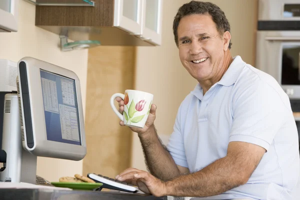 计算机和咖啡微笑的厨房的男人 — 图库照片