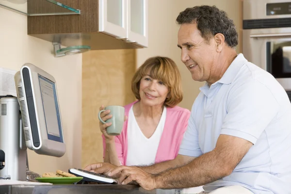 Casal na cozinha com computador e café sorrindo — Fotografia de Stock