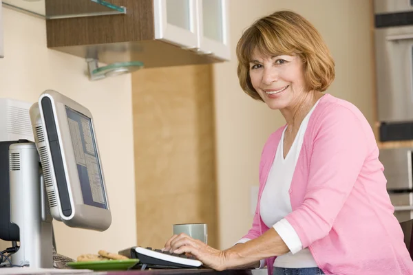 Mujer en la cocina con computadora y café sonriendo —  Fotos de Stock