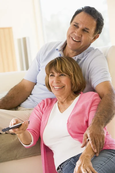 Casal na sala de estar com controle remoto sorrindo — Fotografia de Stock