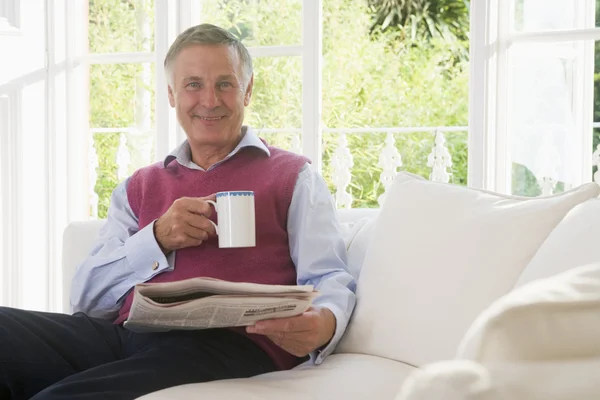Man Woonkamer Met Koffie Lezen Krant Glimlachen — Stockfoto