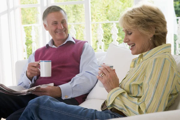Couple in living room with coffee and newspaper smiling — Stock Photo, Image