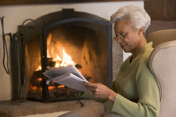 Kvinna i vardagsrummet läsa tidningen — Stockfoto