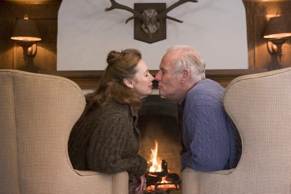 Paar zitten in woonkamer met open haard kussen — Stockfoto
