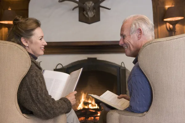 Couple sitting in living room by fireplace with books smiling
