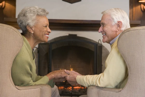 Couple sitting in living room by fireplace holding hands and smi — Stock Photo, Image