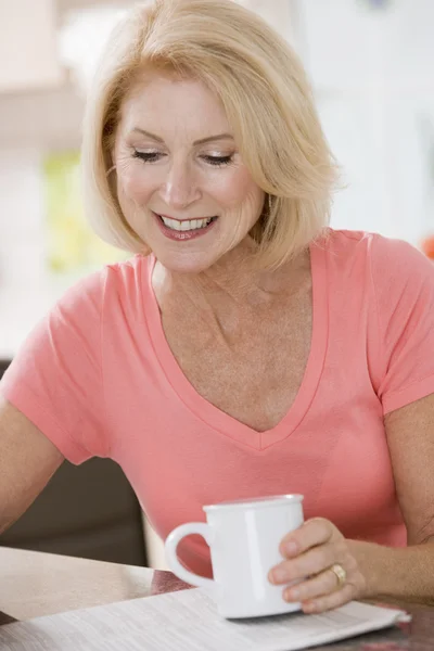 キッチンにはコーヒーと新聞笑顔の女性 — ストック写真