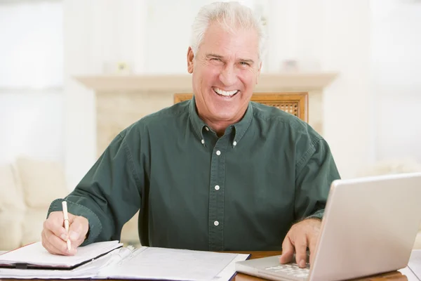 Hombre en el comedor con laptop y papeleo sonriendo —  Fotos de Stock