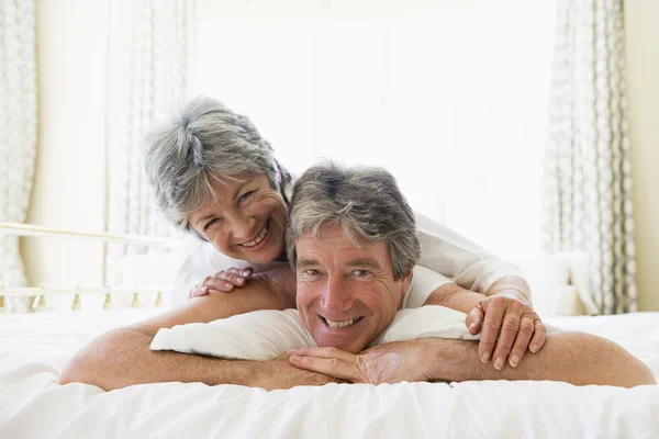 Casal deitado na cama juntos sorrindo — Fotografia de Stock