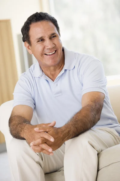 Mann sitzt lächelnd im Wohnzimmer — Stockfoto