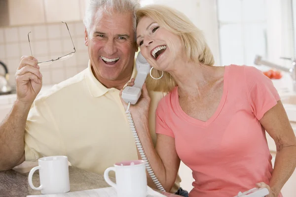 Pareja en la cocina usando el teléfono juntos y riendo — Foto de Stock