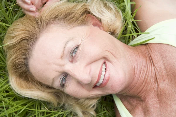 Vrouw liggen in het gras glimlachen — Stockfoto
