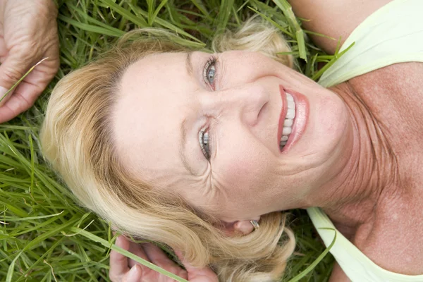 Женщина, лежащая в траве улыбаясь — стоковое фото