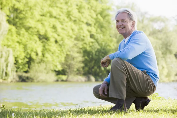 Homem ao ar livre no parque pelo lago sorrindo — Fotografia de Stock