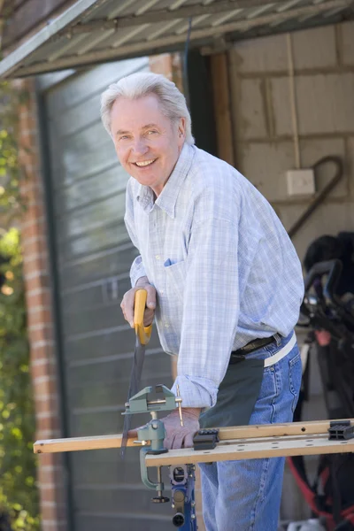 Muž na boudě řezání dřeva a s úsměvem — Stock fotografie