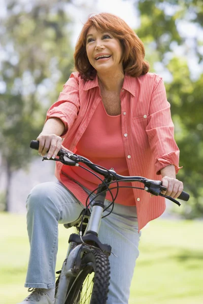 Женщина на велосипеде на улице улыбается — стоковое фото