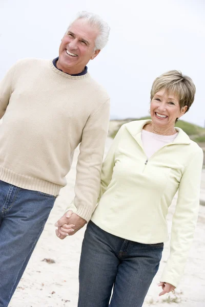 Para na plaży, trzymając się za ręce i uśmiechając się — Zdjęcie stockowe