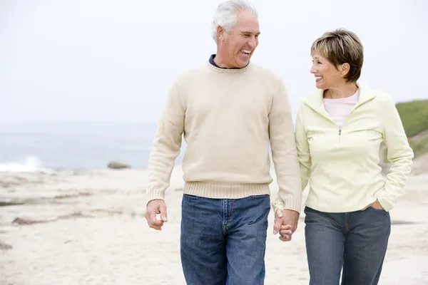 Par på stranden hålla händer och leende — Stockfoto