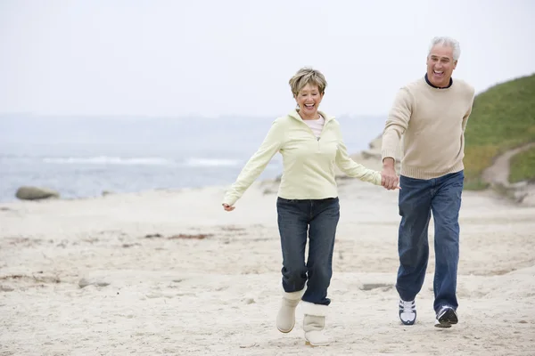 Par på stranden hålla händer och leende — Stockfoto