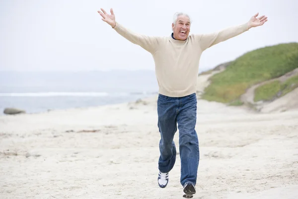 Uomo in spiaggia che corre e sorride — Foto Stock