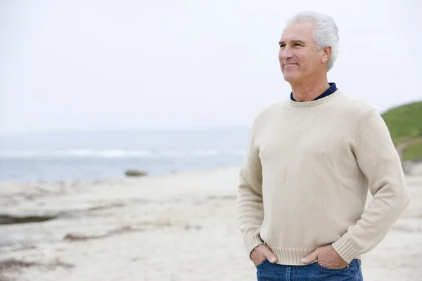 Человек на пляже с руками в карманах — стоковое фото