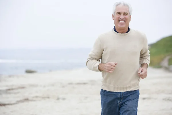 Homem na praia correndo e sorrindo — Fotografia de Stock