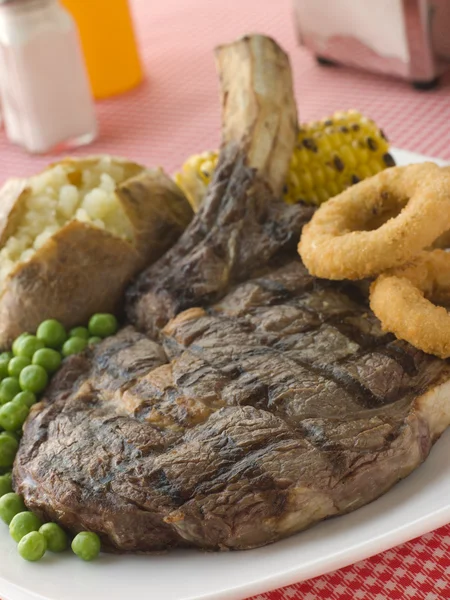 Ribeye Steak na kości z pieczonym groszkiem ziemniaczanym Onion Rings i — Zdjęcie stockowe