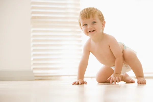 Baby crawling indoors smiling — Stok fotoğraf