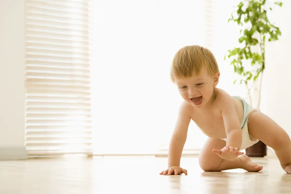 Bebê rastejando dentro de casa sorrindo — Fotografia de Stock