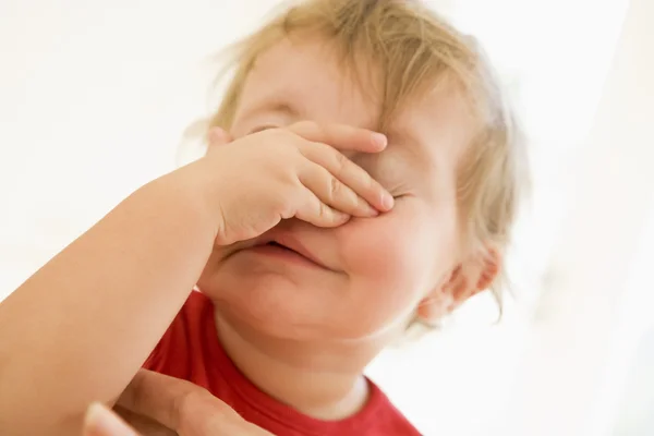 Bebê dentro de casa colocando a mão sobre o rosto — Fotografia de Stock