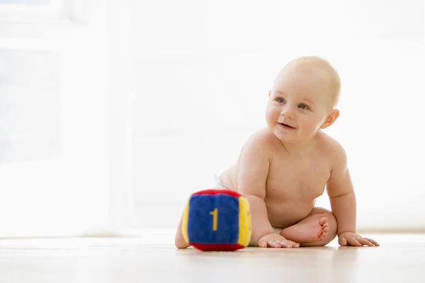 Bebé sentado en el interior con bloque sonriendo — Foto de Stock