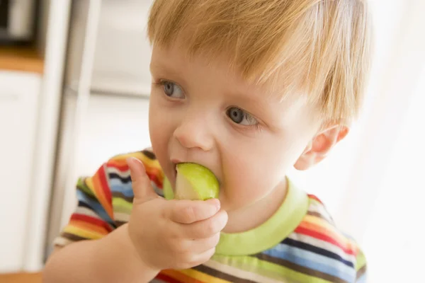 Jeune garçon mangeant des pommes à l'intérieur — Photo