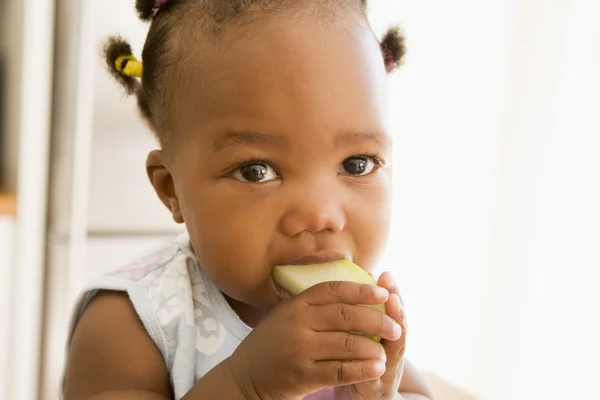 Молодая девушка ест яблоко в помещении — стоковое фото