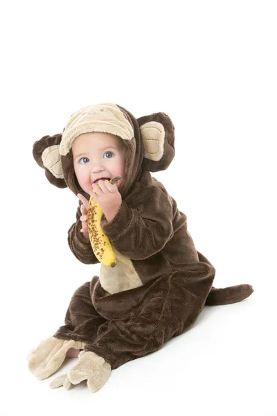Bebé en traje de mono sosteniendo plátano — Foto de Stock