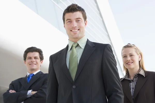 Três empresários de pé ao ar livre, construindo sorrindo — Fotografia de Stock