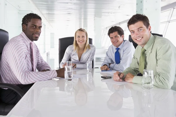 Vier ondernemers in een directiekamer glimlachen — Stockfoto