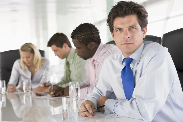 Quatro empresários numa sala de reuniões a escrever: — Fotografia de Stock