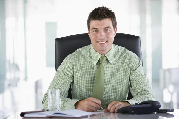 Zakenman zitten in kantoor met persoonlijke organizer lachende — Stockfoto