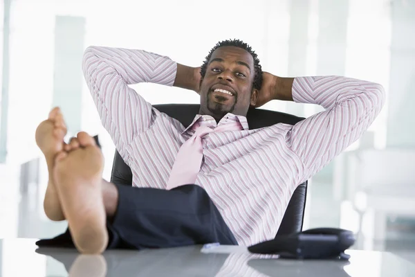 Geschäftsmann sitzt im Büro mit den Füßen auf dem Schreibtisch und entspann — Stockfoto