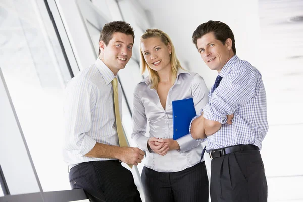 Tre företagare står i korridoren leende — Stockfoto