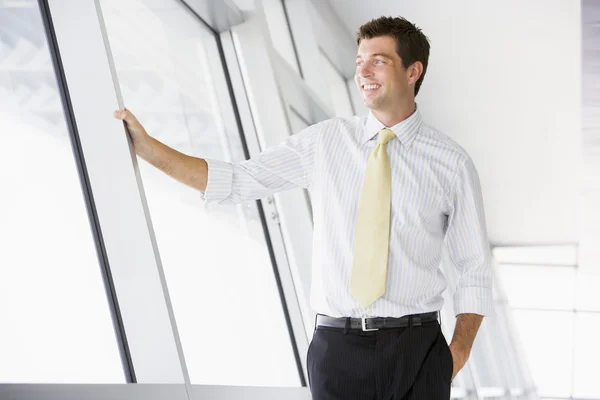Empresário em pé no corredor sorrindo — Fotografia de Stock