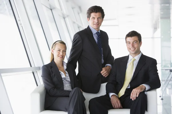 Τρεις Επιχειρηματίες Που Κάθεται Στο Γραφείο Λόμπι Χαμογελώντας — Φωτογραφία Αρχείου