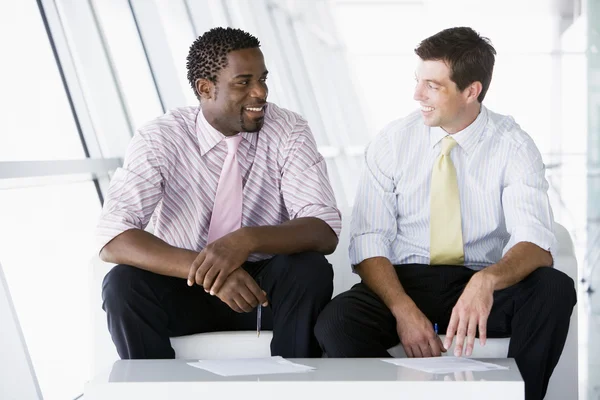 坐在办公室的两个商人游说说话和笑 — 图库照片